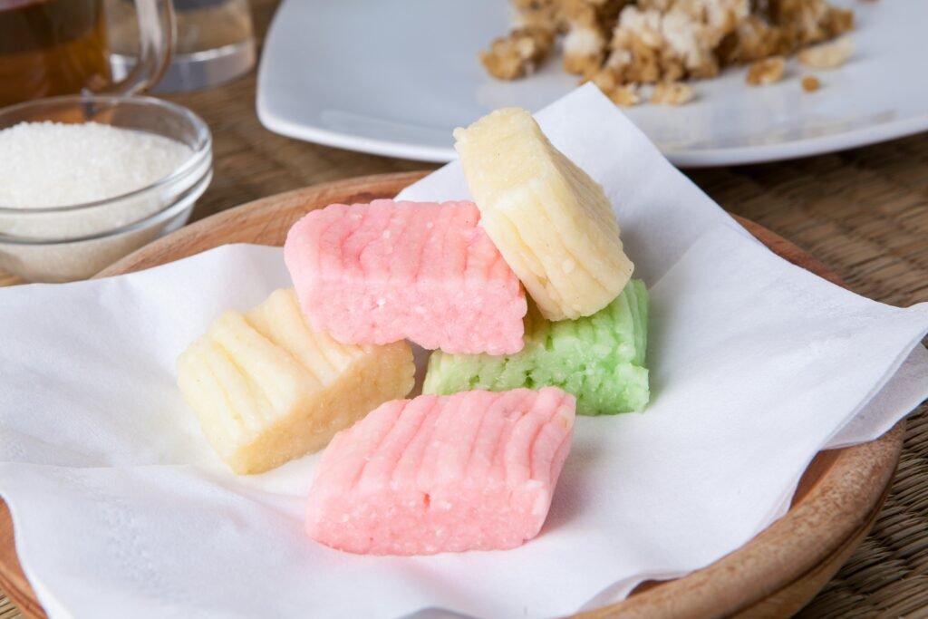 A close-up of colorful Getuk Lindri, a traditional Indonesian cassava snack served on a wooden plate.